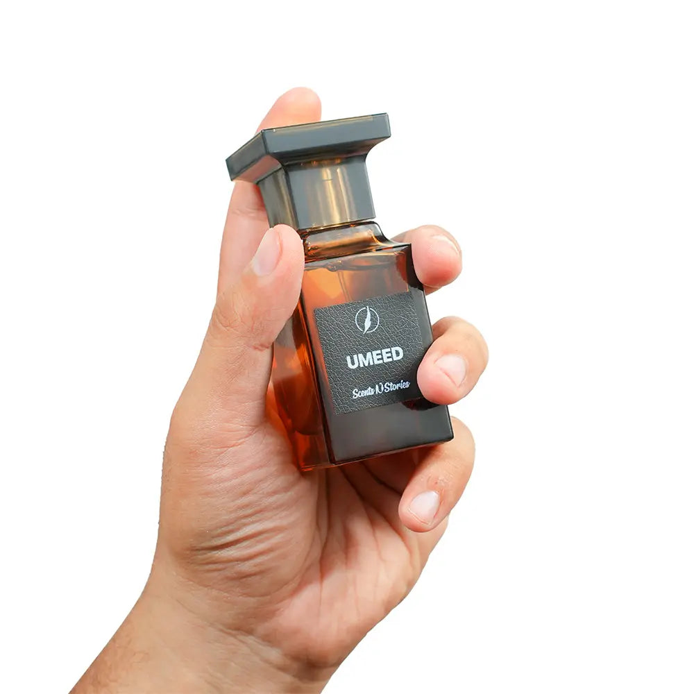 Hand holding a UMEED perfume bottle against a white background