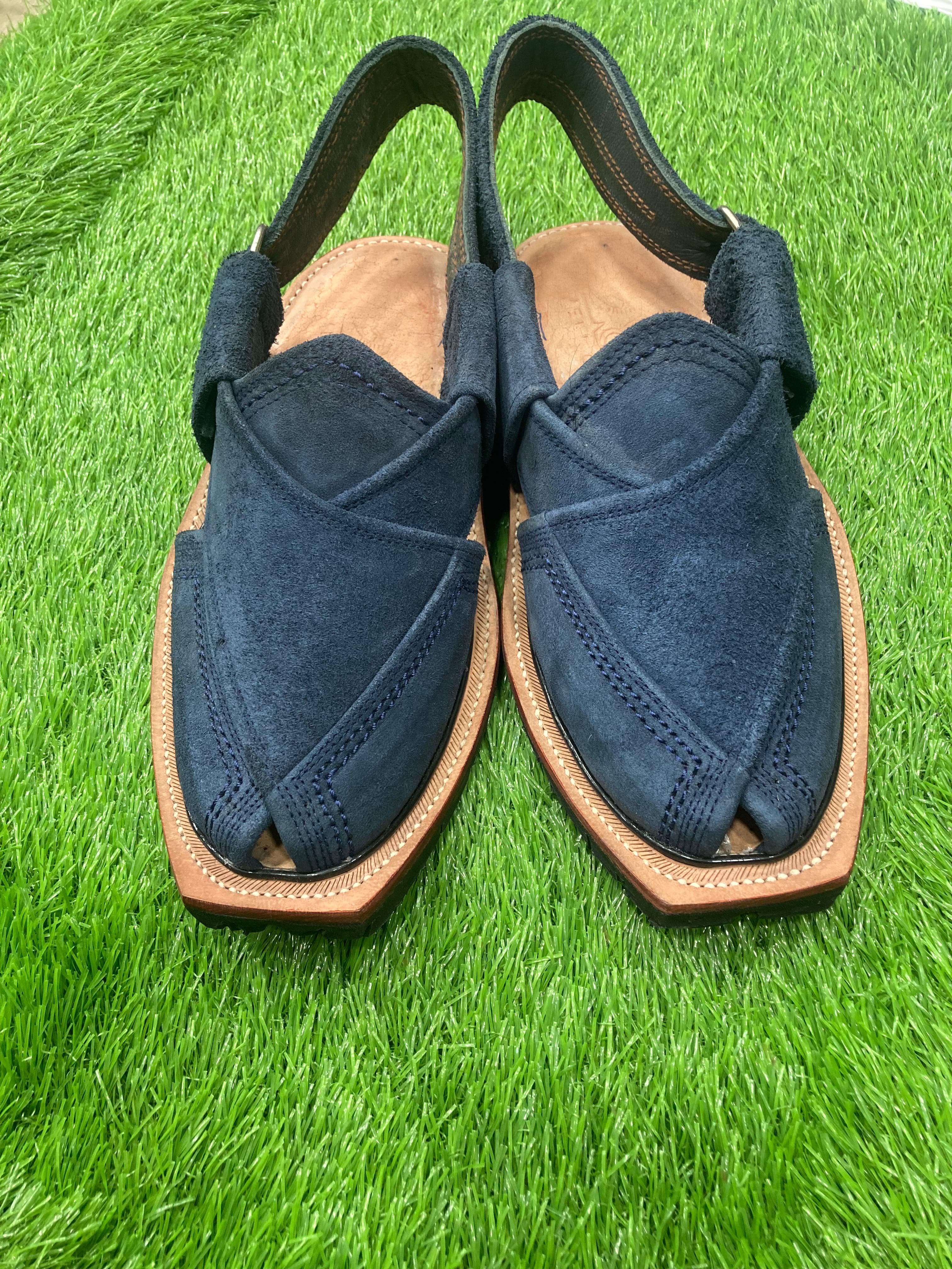 Pair of blue sandals with brown soles on a green grass background